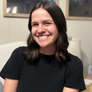 Jennifer Hartmus sitting in comfortable chair with artwork in the background